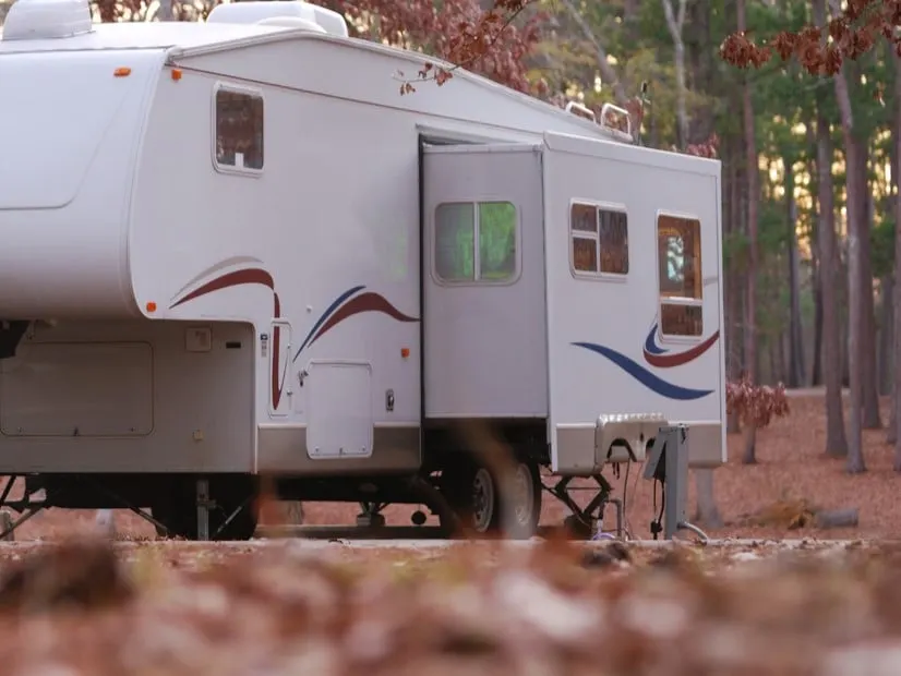 A camper trailer parked and set up at a campground. You can find hookups and stay within your RV budget.