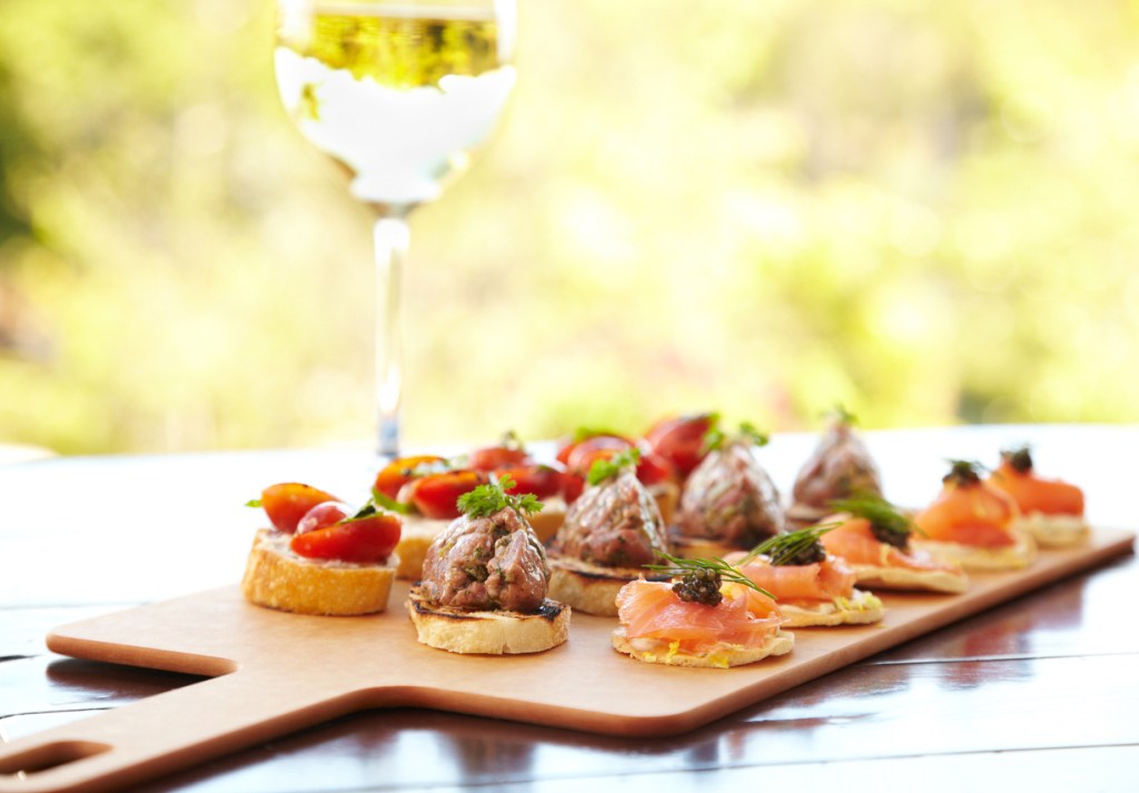 Fancy hors d'ouevres and a glass of white wine like you might see at a food festival