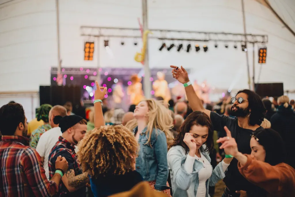 Group of friends dancing together at an outdoor music festival.