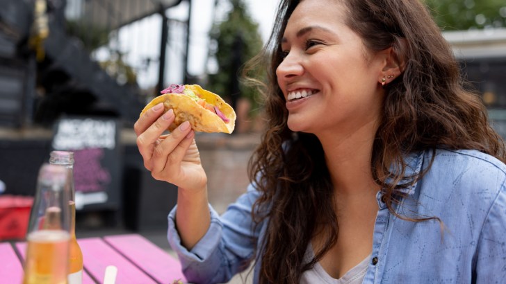 A happy woman eating a taco, maybe somewhere in Arizona