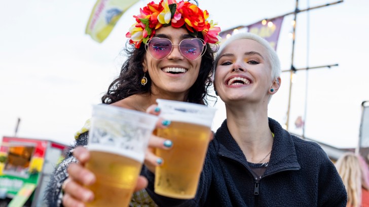 Two women holding cups of beer at a festival