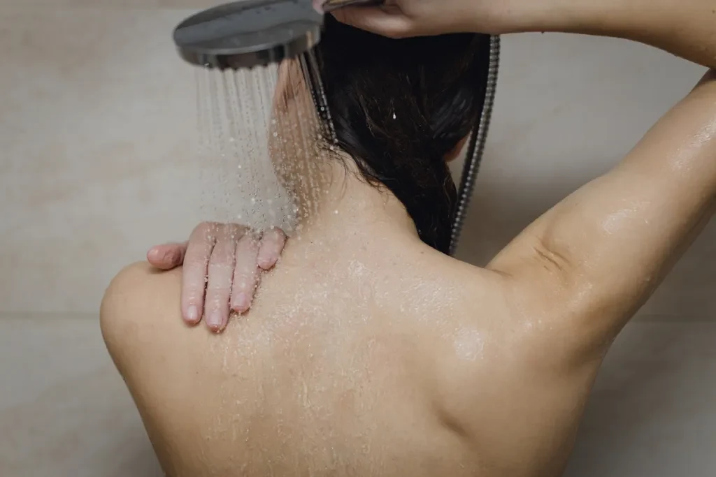 Woman holding a budget shower head and taking a shower
