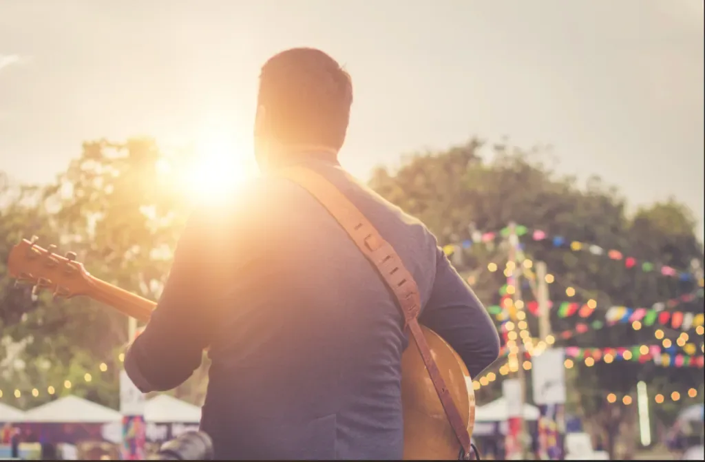 A man playing guitar at an outdoor music festival
