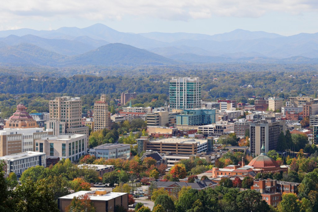 Aerial photograph of Asheville with mountains in the background. 
