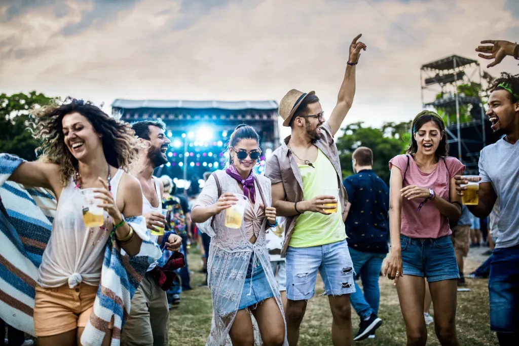 A group of friends dances under the open sky at a music festival.
