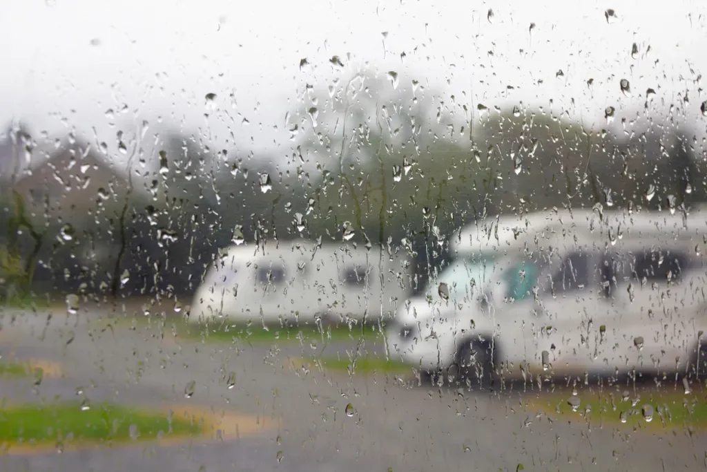 View of an RV campground through a rain-covered window. 