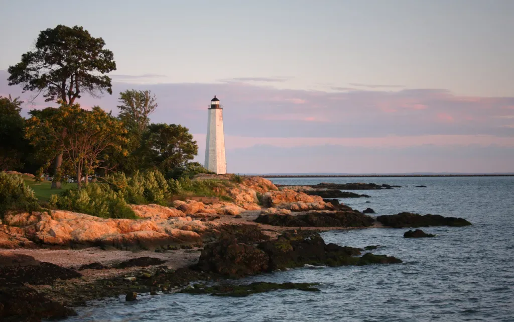 A white lighthouse overlooks the rocky shores on Connecticut's Atlantic coast.