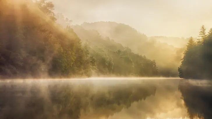 A misty lake surrounded by mountains, perhaps in one of Tennessee's state parks.
