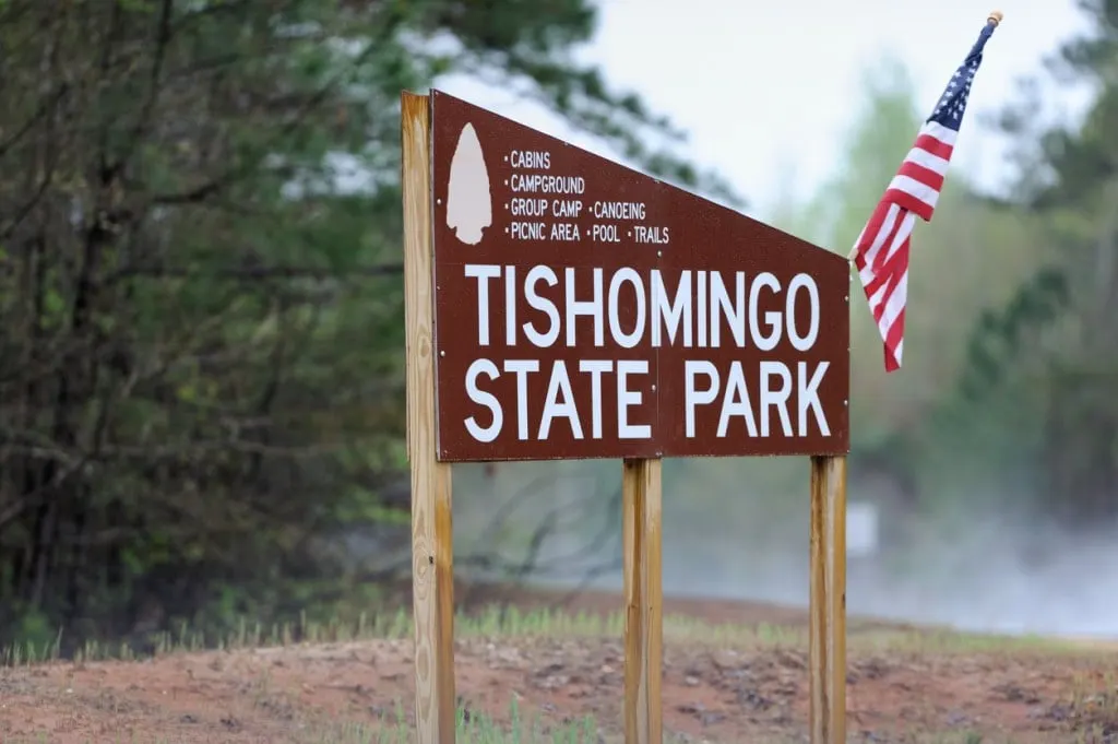 The welcome sign for Tishomingo State Park in Mississippi, decorated with an American flag.