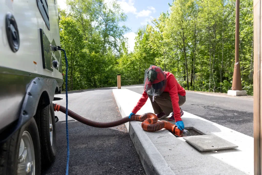 An RVer empties their sewage at a dump station. Judging by their head-to-toe outfit, we assume they didn't use an RV black tank treatment. 