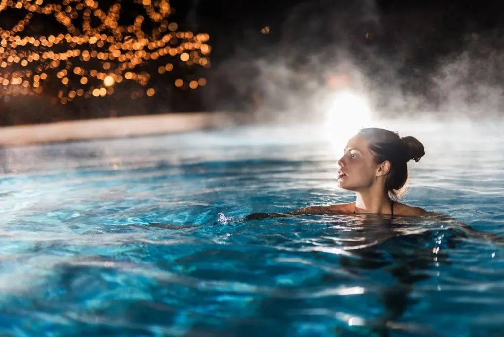 A woman soaking in hot springs at night, perhaps in California