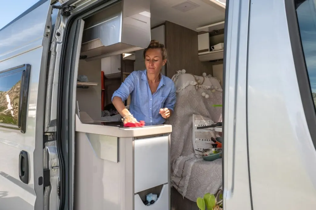 A woman cleaning inside a camper van. You'll need to clean the RV rental before returning it.