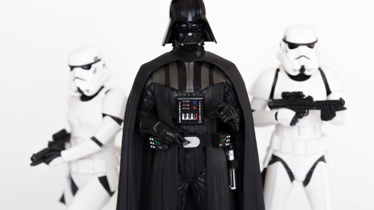 Darth Vader stands next to two Stormtroopers.