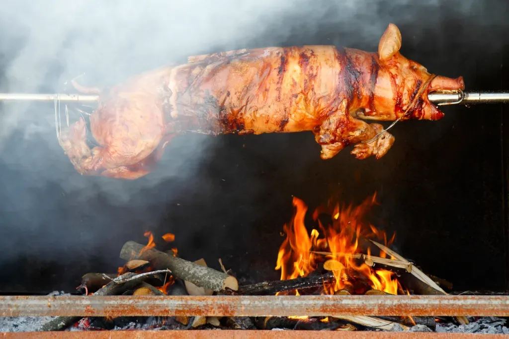 A whole pig roasts over an open flame.