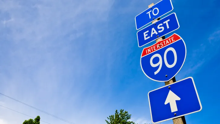 I-90 road sign against a bright blue sky.