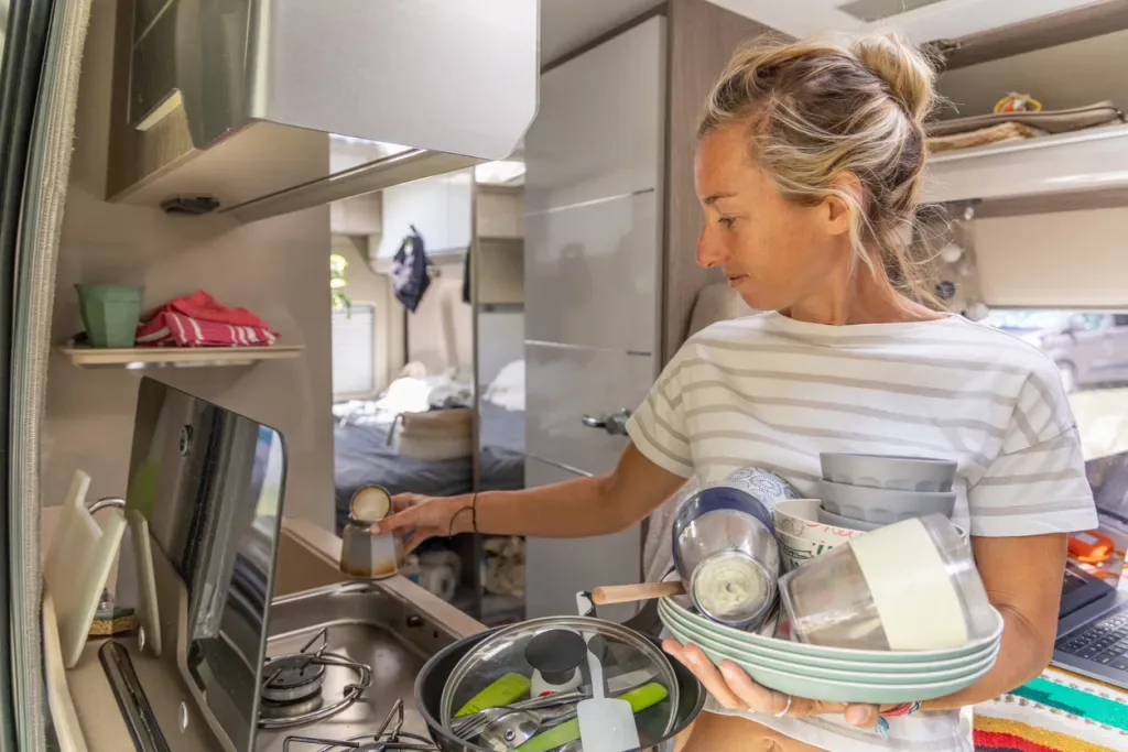 A woman does dishes in her camper. Based on the amount of cookware, it seems she hasn't embraced tiny living. 